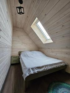 a bed in a wooden room with a window at Gabrysiówka in Sztabin
