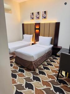 a hotel room with two beds and a desk at Blue Sky Way Hotel in Dubai