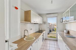a white kitchen with a sink and a counter at Superbe T3 Villeurbanne Centre avec climatisation in Villeurbanne +6 photos