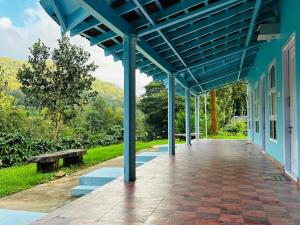 a blue building with a walkway and a bench at Coorg Island Cafe & Cottages by StayApart in Madikeri
