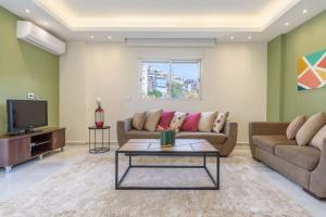 a living room with two couches and a tv at Kali - Charming 2-BR Apt & Balcony in Antelias in Anţilyās
