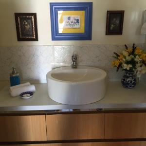 a white sink in a bathroom with flowers on a counter at Airport Riverview Motel in Brisbane