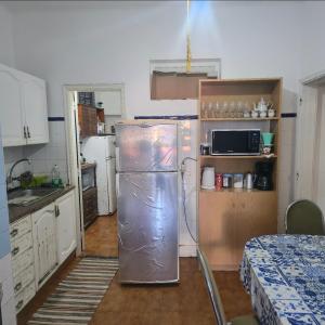 a kitchen with a refrigerator in the middle of a room at Quarto individual in Mafra