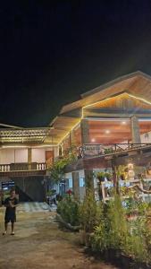 a person standing in front of a building at night at Toraja Sanggalangi Homestay in Rantepao