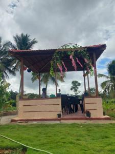 a man sitting on a bench under a pavilion with flowers at Friendly homestay in Mysore