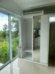 einen weißen Schrank in einem Zimmer mit Fenster in der Unterkunft The Green Valley Escape in Ban Ko Khwan