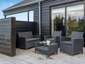 Un patio con sillas y una mesa en una terraza. en Holiday Home Øthbiorn - 1-1km from the sea by Interhome, en Løkken