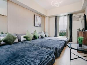 two beds in a room with a couch and a table at NEW Comfy 1BR Cebu IT Park Location in Cebu City +42 photos