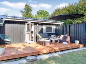 a wooden deck with an umbrella on a backyard at Holiday Home Zoya - 470m from the sea by Interhome in Gedser +12 photos