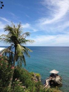 una palmera junto al océano con una mesa y una sombrilla en Anoi Itam Resort en Sabong