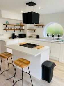 a kitchen with a white counter and two stools at 2 bedroom cottage in Bromley suitable for 4 people in Bickley