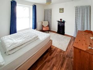 a bedroom with a large bed and a chair at Rockhopper Cottage in Brixham +4 photos