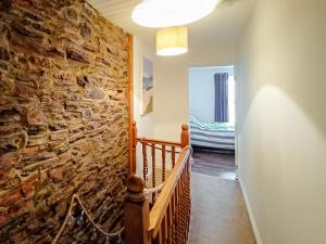 a hallway with a stone wall and a staircase at Rockhopper Cottage in Brixham
