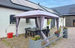 a table and chairs under a purple umbrella at 1 Bedroom Beautiful Apartment In Vallåkra in Ekeby