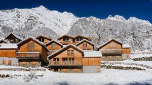a lodge in the snow with mountains in the background at Chalet Le Refuge in Vaujany