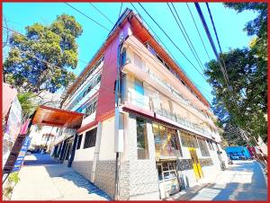 a red and white building on the side of a street at HOTEL THE MOON - Near Mall Road & Naini Lake View - LIFT -Free Parking -Restaurant -Wi-Fi Available- Ambience with Valley- A Top Rated Hotel IN Nainital in Nainital