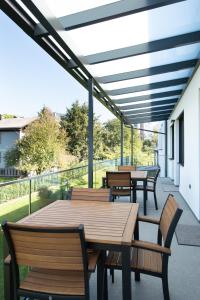 un patio con mesas de madera y sillas en el balcón en Frant Living - Graz Apartments, en Graz