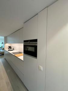Una cocina con gabinetes blancos y un horno de estufa. en Bright and spacious duplex apartment by the sea - De Panne, en De Panne
