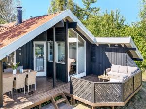 a house with a deck with a couch and a table at Holiday Home Ama - 250m from the sea by Interhome in Knebel