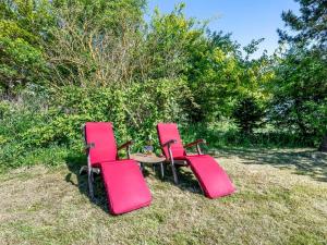 three red chairs and a table in the grass at Holiday Home Ama - 250m from the sea by Interhome in Knebel +17 photos