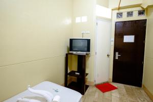 um pequeno quarto com uma televisão e uma porta em GV Hotel - Pagadian em Pagadian