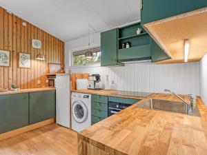 a kitchen with green cabinets and a washing machine at Holiday Home Rikkart - 400m from the sea by Interhome in Dannemare +13 photos