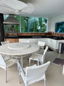 a dining room with a table and chairs and a kitchen at Toninhas Beach - Gated Community - Ubatuba-SP in Ubatuba
