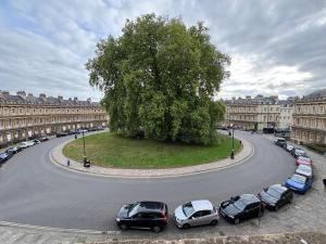 a street with cars parked around a tree in a city at Pulteney Road Apartment in Bath +56 photos