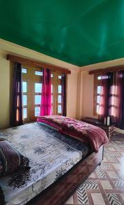 a bedroom with a large bed with a green ceiling at Iris cafe and cozy stay in Tosh