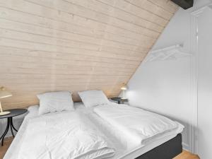 a bedroom with a white bed with two tables at Holiday Home Erle - 830m from the sea by Interhome in Nyby +17 photos