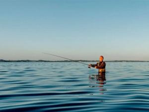 a man in the water fishing in the water at Holiday Home Har - 1-2km from the sea by Interhome in Sæby