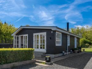 una pequeña casa negra con chimenea en Holiday Home Welma - 200m from the sea by Interhome, en Frederikshavn