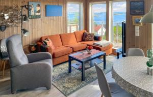 a living room with an orange couch and a table at Lovely Home In Sandviga With House Sea View in Skarvedalen