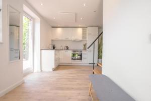 a kitchen with white cabinets and a wooden floor at Nordstrander Küstenlodge - Sternentraum in Nordstrand