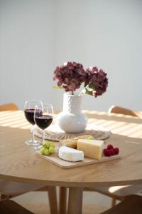 a table with two glasses of wine and cheese and flowers at 3 Bedroom Nordic Timber Home in Kokkola