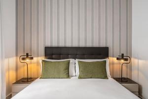 a bedroom with a white bed with two lamps at Aspasios Catedral Apartments in Barcelona +17 photos