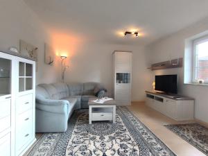 a living room with a couch and a tv at FeWo Unter den Linden in Wallsbüll +10 photos