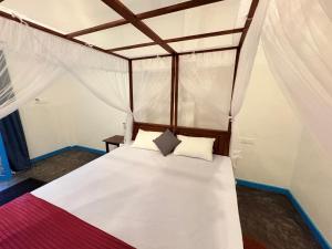 Un dormitorio con una cama con dosel con sábanas y almohadas blancas. en Villa Komalee, en Unawatuna 26 fotos más