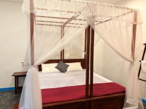 a bedroom with a canopy bed with white curtains at Villa Komalee in Unawatuna