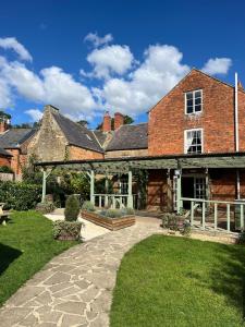 a large brick house with a patio and a yard at The George Inn in Lower Brailes