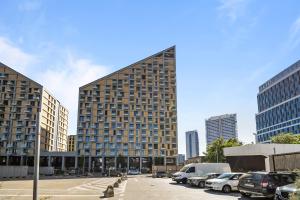 a tall building with cars parked in a parking lot at 1,5 room AC apartment, balcony,new building, Downtown, Old City in Nivy