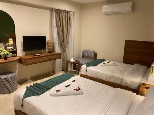 a hotel room with two beds and a television at NOMAD PYRAMIDS AND SPHINX Hotel in Cairo