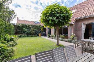 a yard with two benches and a tree at Vrijvakantiehuis Herenhof in Domburg