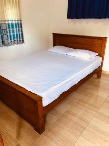 a bed with white sheets and pillows in a room at Ramira Holiday Bungalow in Moragaswewa