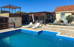 a swimming pool with chairs and a house at Nice Home In Benkovac in Benkovac