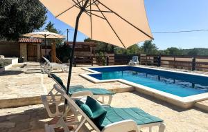 a pool with chairs and an umbrella next to it at Nice Home In Benkovac in Benkovac +28 photos