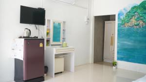 a kitchen with a refrigerator and a desk with a tv at Baan Gamnan Resort Krabi in Ban Khao Ngam