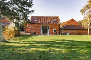 a red brick house with a grass yard at Luxury barn Retreat - sleeps 2-4, quiet location with parking in Wymondham