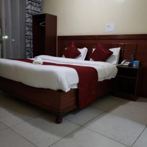 Un dormitorio con una cama grande con almohadas rojas. en Capital Comfort Hotel, en Nairobi