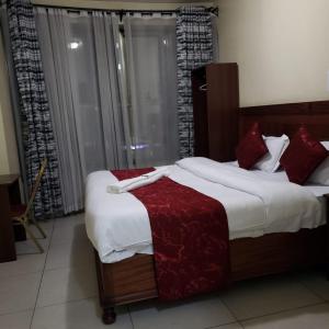 Un dormitorio con una cama grande con almohadas rojas. en Capital Comfort Hotel, en Nairobi 31 fotos más